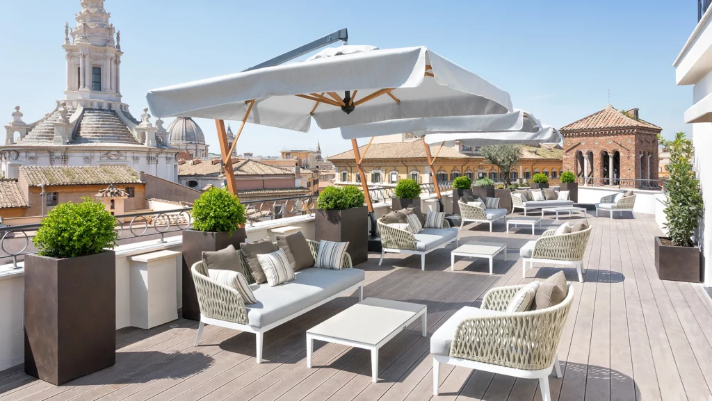 Terrazza panoramica The Pantheon Iconic con pavimento in legno, divanetti e poltrone e ombrelloni da sole