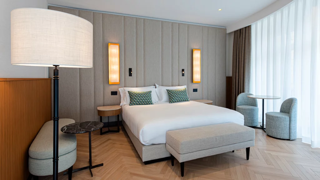 Camera d’albergo contemporanea con letto matrimoniale, testiera imbottita e illuminazione integrata a parete