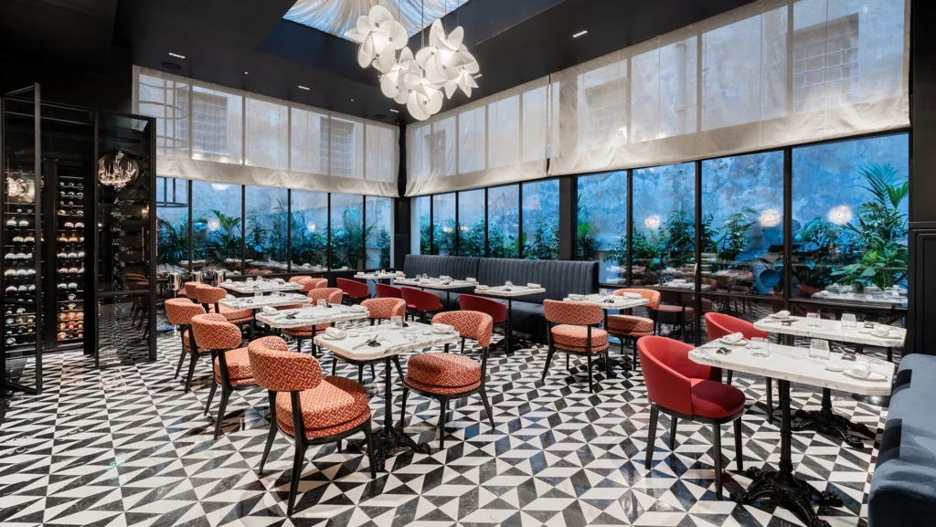 Ristorante con pavimento a mosaico geometrico, sedute rosse e arancioni e ampie vetrate sul giardino antonacci falegnamerie