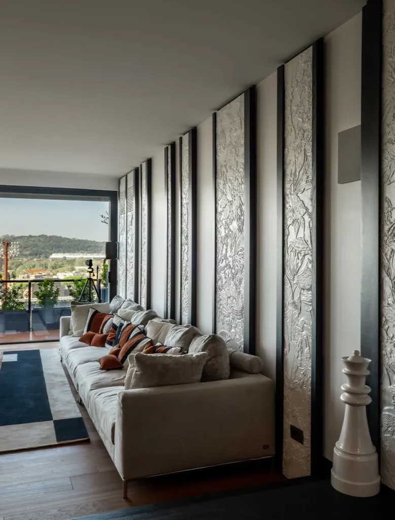 Lato del soggiorno con divano e boiserie personalizzate sulle pareti che raffigurano trame ispirate alla foresta e alla natura