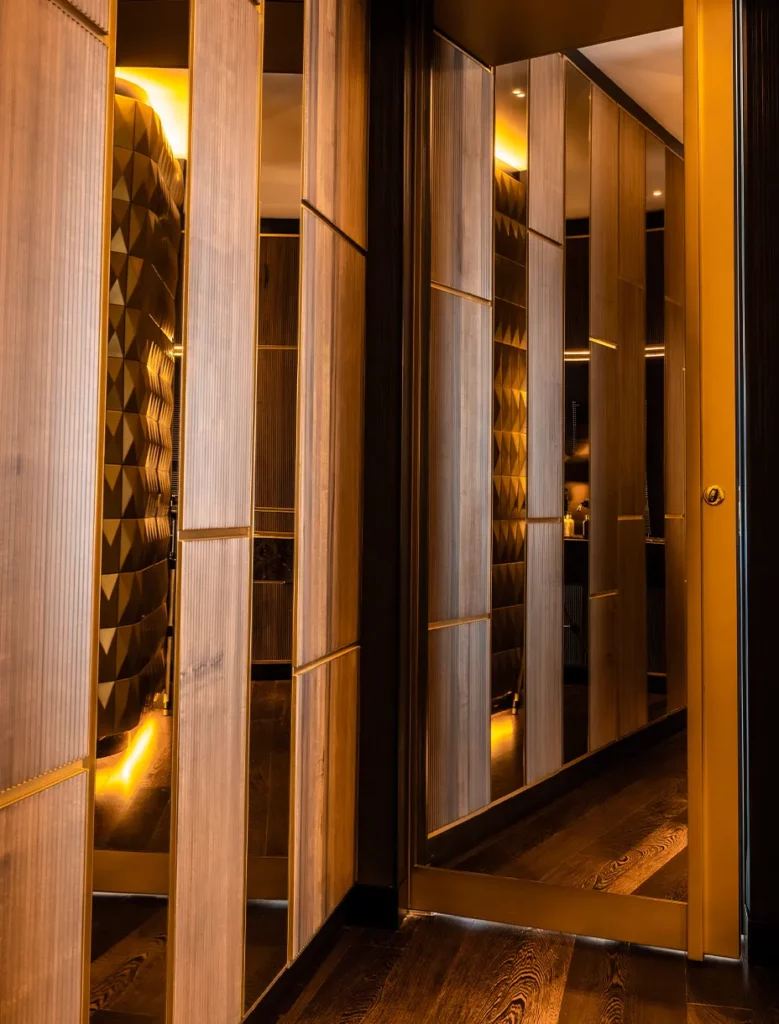 Porta d'ingresso della camera da letto decorata con specchi e armadio in legno laterale