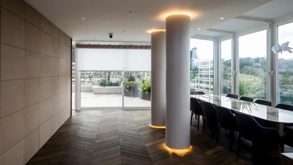 Sala da pranzo con colonne illuminate e tavolo in marmo. Vetrata sul fondo della stanza che affaccia sul terrazzo