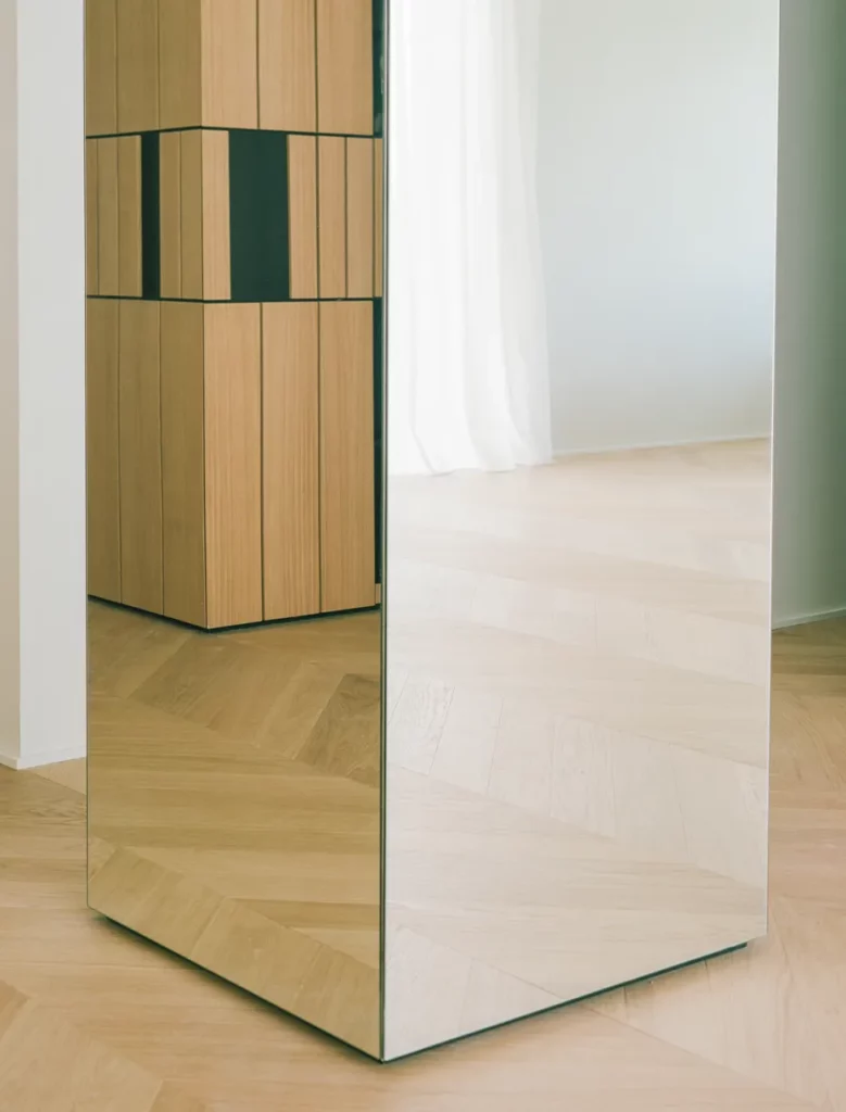 Armadio a specchio con riflesso sul pavimento in rovere chiaro a spina di pesce