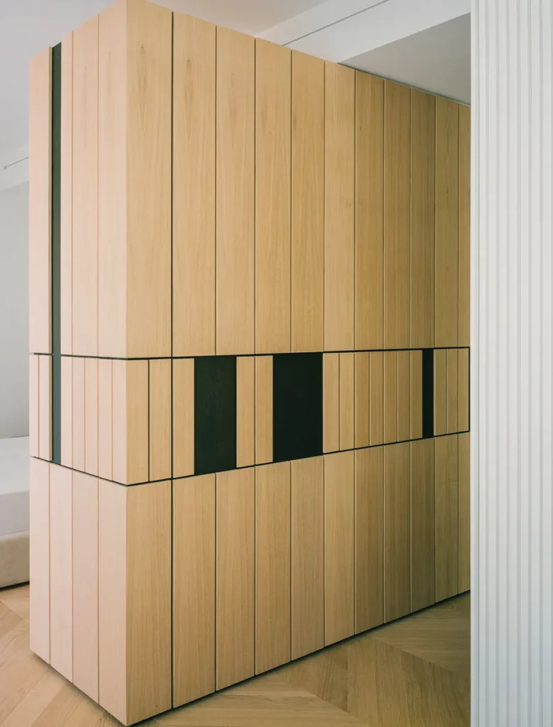 Mobile su misura in legno con pannelli verticali realizzato da falegnameria artigianale e pavimento in rovere a spina di pesce