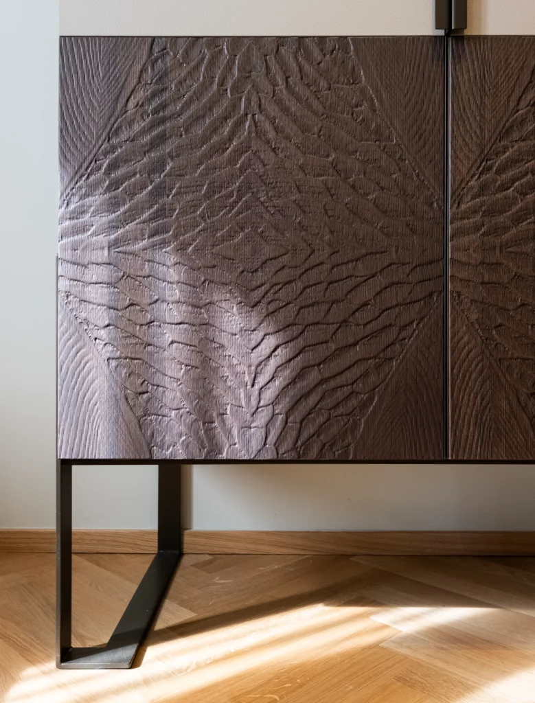 Dettaglio pannellatura incisa a mano in legno scuro, texture tridimensionale realizzata dal laboratorio artigianale Antonacci.